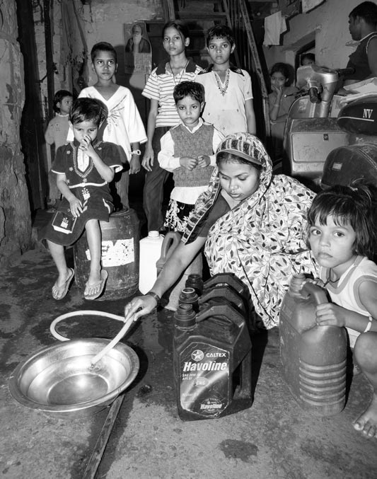 Human Right to Water in Delhi - Filling containers with water trickle from a local piped water network n an unauthorized colony in Delhi